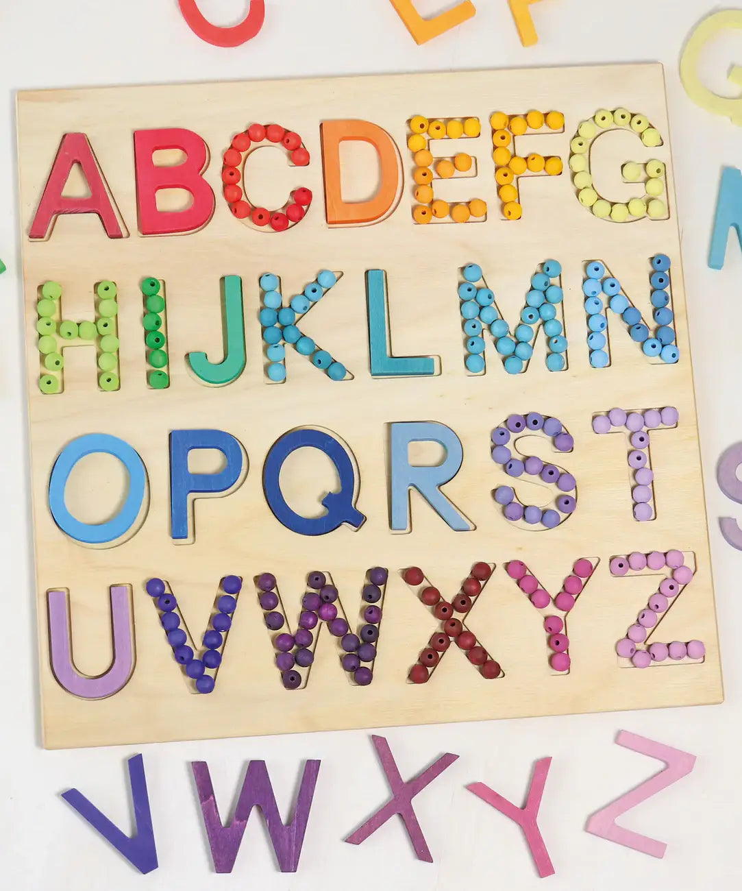Grimms wooden alphabet board with the rainbow and pastel 12mm beads filling in the letter cut outs