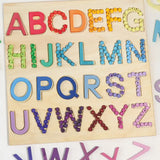 Grimms wooden alphabet board with the rainbow and pastel 12mm beads filling in the letter cut outs