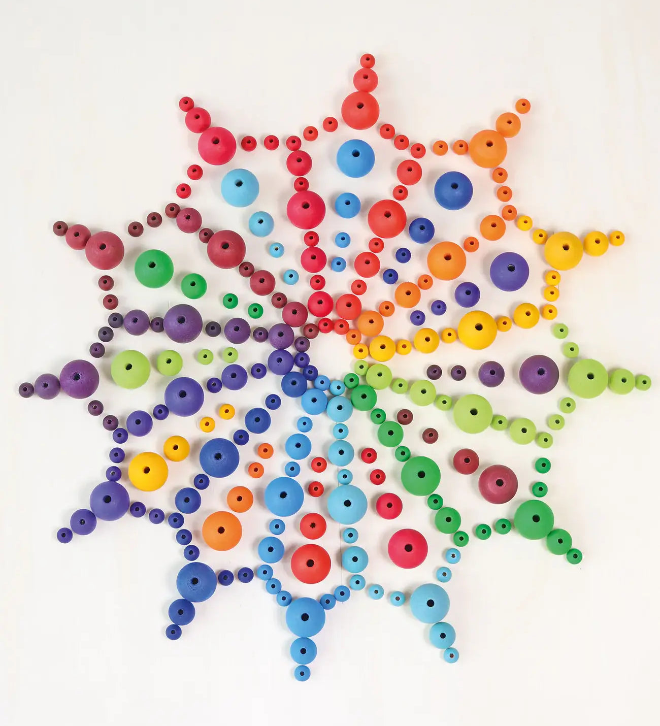 A mandala flatlay made from Grimms handcrafted wooden beads in a rainbow palette