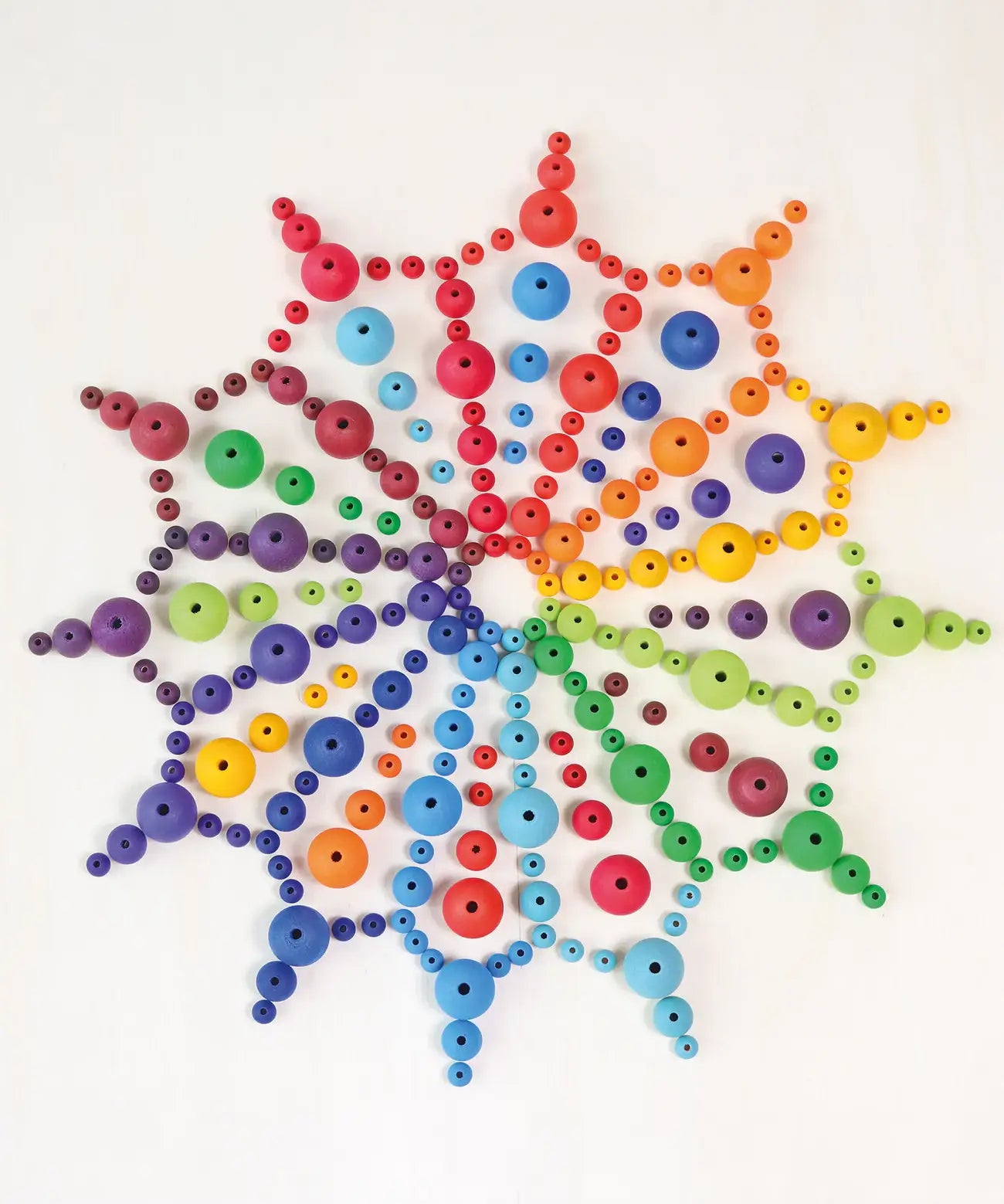 A mandala flatlay made from Grimms handcrafted wooden beads in a rainbow palette