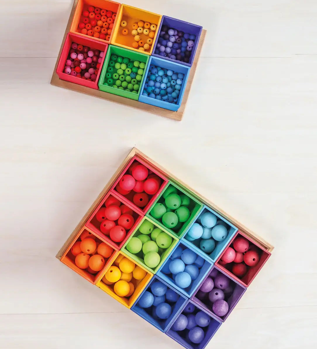 Grimms 20mm and 12mm handcrafted beads in a rainbow palette sorted into matching coloured trays