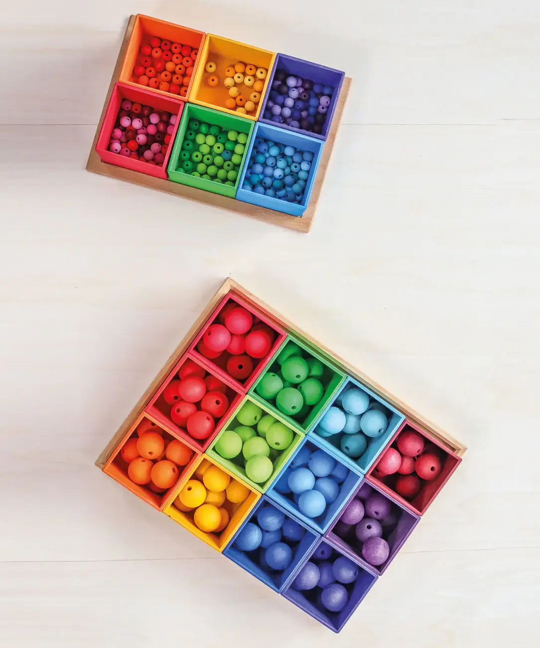 Grimms 20mm and 12mm handcrafted beads in a rainbow palette sorted into matching coloured trays