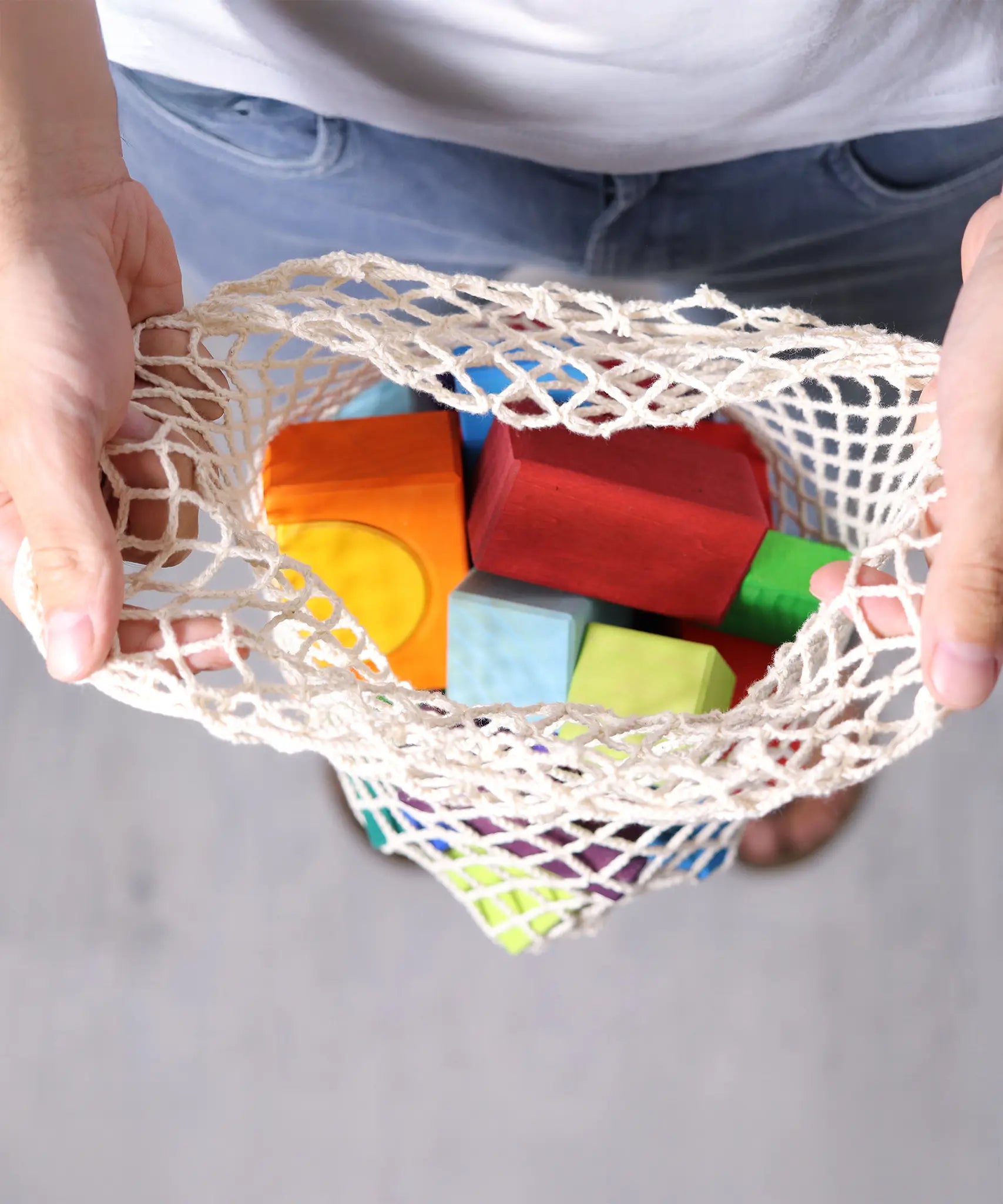 Grimm's 30 Coloured wooden Geo Blocks in their netting storage bag.