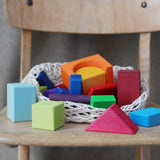 Grimm's 30 Coloured wooden Geo Blocks placed on a wooden chair.