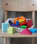 Grimm's 30 Coloured wooden Geo Blocks placed on a wooden chair.