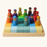 Set of 36 Grimms bright rainbow wooden rainbow cubes in a frame with peg dolls on top