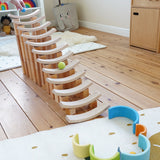 A ball run made from wooden blocks with Grimms pastel balls travelling down. Standing in the Babipur playroom