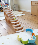 A ball run made from wooden blocks with Grimms pastel balls travelling down. Standing in the Babipur playroom