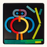 A abstract character made from the Grimm's bright wooden A-Z curved and straight magnetic pieces displayed in a tin 
