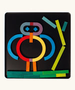 A abstract character made from the Grimm's bright wooden A-Z curved and straight magnetic pieces displayed in a tin 