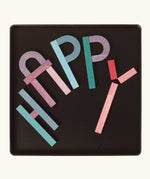 The word 'HAPPY' made from the Grimm's bright wooden A-Z curved and straight magnetic pieces displayed in a tin 