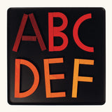 Letters of the alphabet made from the Grimm's bright wooden A-Z curved and straight magnetic pieces displayed in a tin 