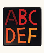 Letters of the alphabet made from the Grimm's bright wooden A-Z curved and straight magnetic pieces displayed in a tin 