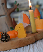 A close up of a Grimm's Autumn dwarf decorative figure placed on a natural celebration ring. 