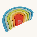 The Grimm's Babi Gwawr Sunrise 6 Piece Rainbow on a plain background. The rainbow is shown it's side showing the bottom of the rainbow. The Grimm's and babipur logo's can be seen on the bottom of the red piece. 