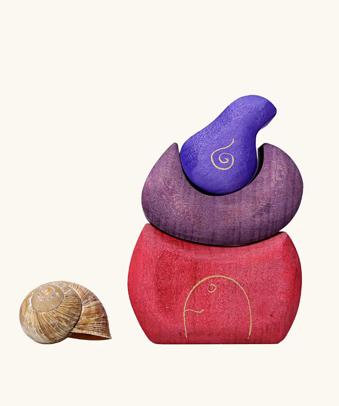 Grimm's purple bakery block house wooden toy next to a snail shell. 