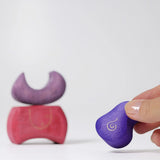 Piece of the Grimm's purple bakery block house wooden toy shown in an adult's fingers.