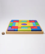 The Grimm's Basic Building Set 2 wooden block set shown in it's wooden storage tray next to a snail's shell. 