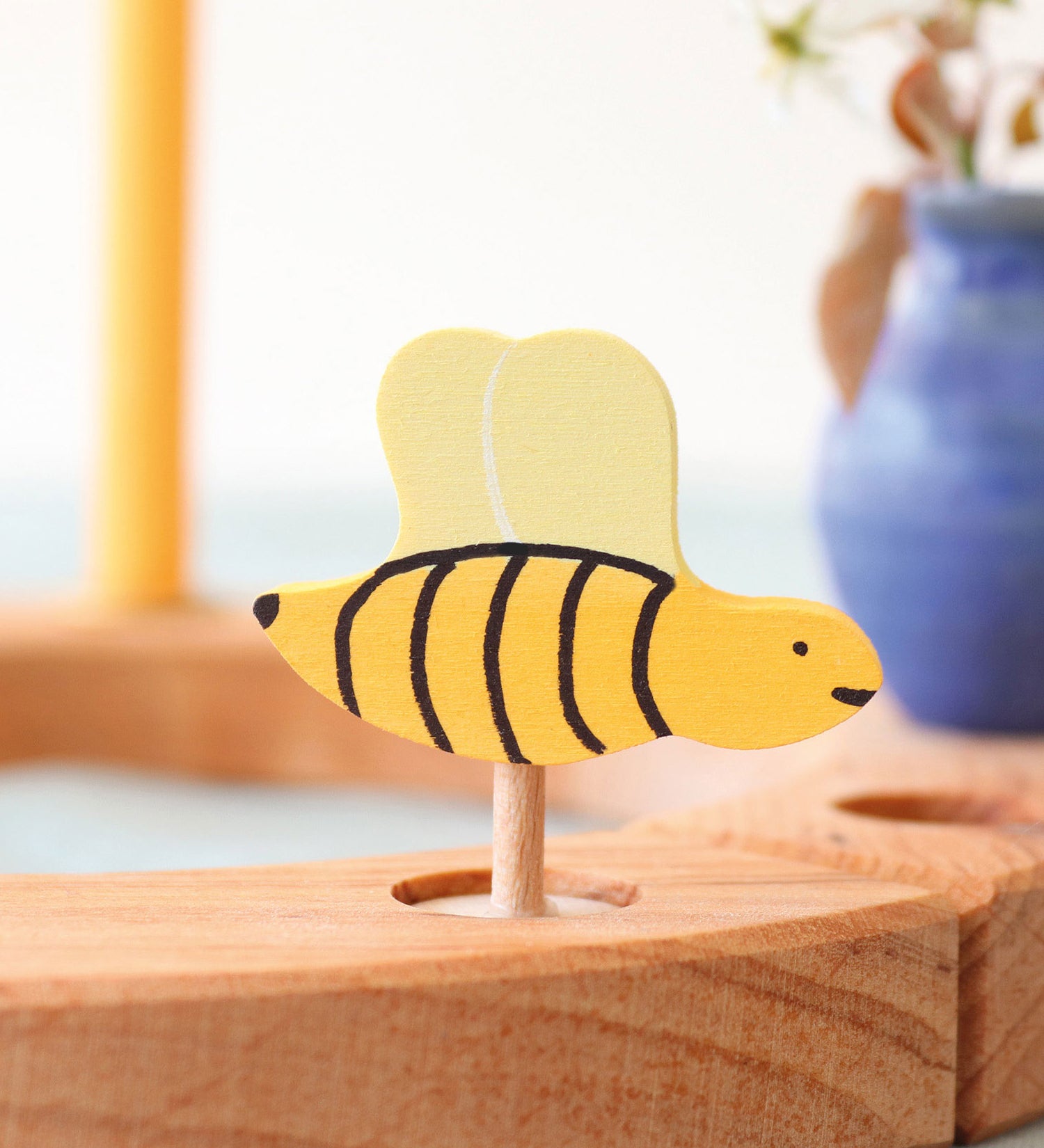 A Grimm's bee decorative figure placed on a natural Grimm's celebration ring. The bee is part of a wide range of Waldorf inspired decorative figures available here at Babipur. 