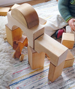 Child playing with the Grimm's giant natural wooden building blocks set.