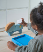 A child playing with the Grimm's blue boat Wooden Stacking Puzzle. The child is stacking the blocks on top of each other. These Grimm's toys are part of a wide range of wooden toys available here at Babipur. 