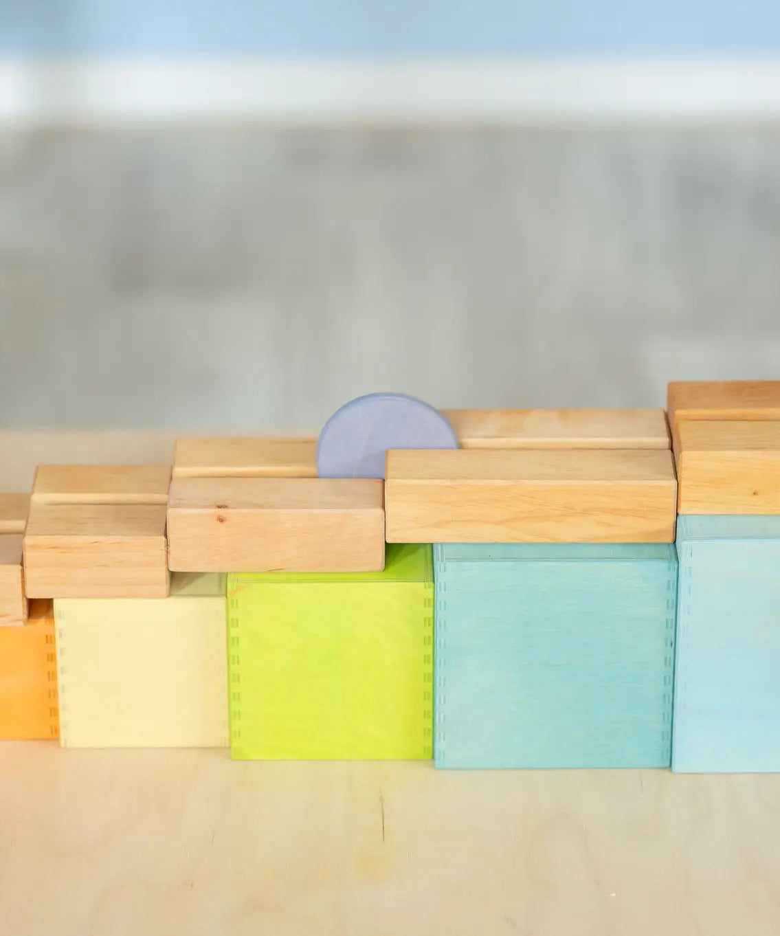 A coin down a wooden rail on top of the Grimms large pastel building boxes