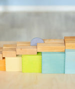 A coin down a wooden rail on top of the Grimms large pastel building boxes