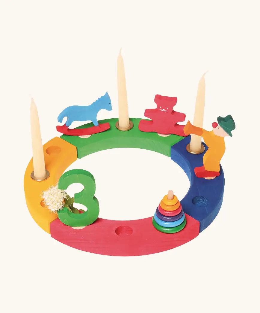 Grimms bright wooden celebration ring pieces displaying decorative figures including a rocking horse, teddy bear, clown conical tower and a number 3 figure
