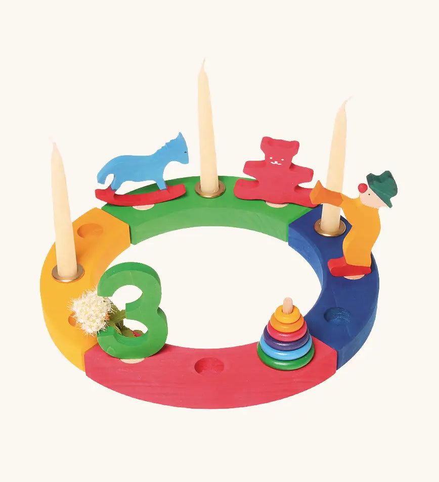 Grimms bright wooden celebration ring pieces displaying decorative figures including a rocking horse, teddy bear, clown conical tower and a number 3 figure