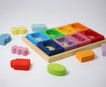 Grimm's Windows Building Set wooden blocks in a wooden storage tray. The shaped inserts from the window blocks have been taken out and placed around the tray. These Grimm's wooden blocks are part of a wide range of wooden toys available here at Babipur. 