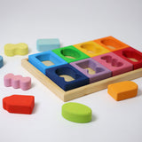 Grimm's Windows Building Set wooden blocks in a wooden storage tray. The shaped inserts from the window blocks have been taken out and placed around the tray. These Grimm's wooden blocks are part of a wide range of wooden toys available here at Babipur. 