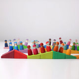 Grimm's sloping blocks building set blocks lined up with friends peg dolls placed on top of them.