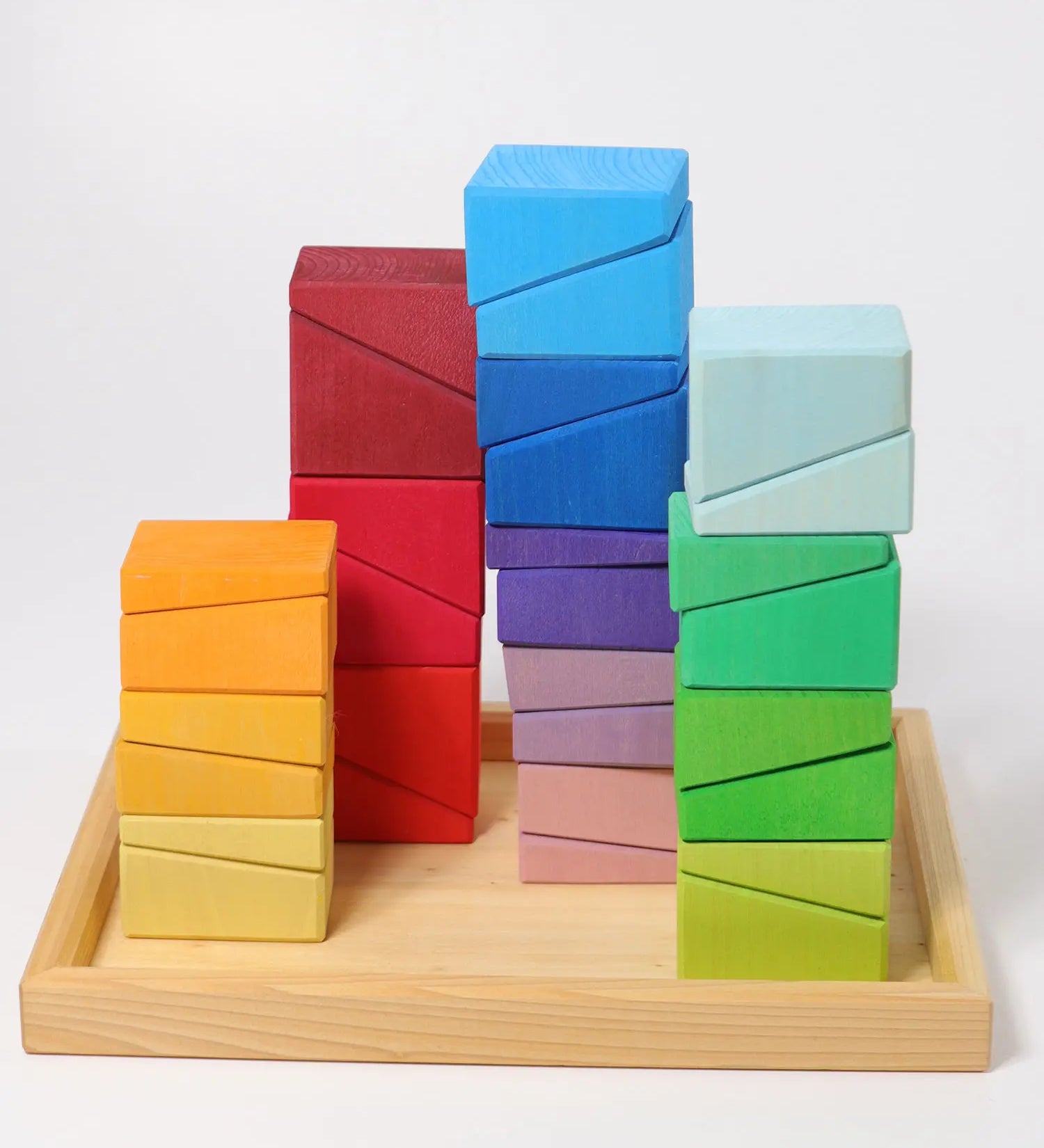 Grimm's sloping blocks building set blocks shown stacked up on the wooden storage display tray.