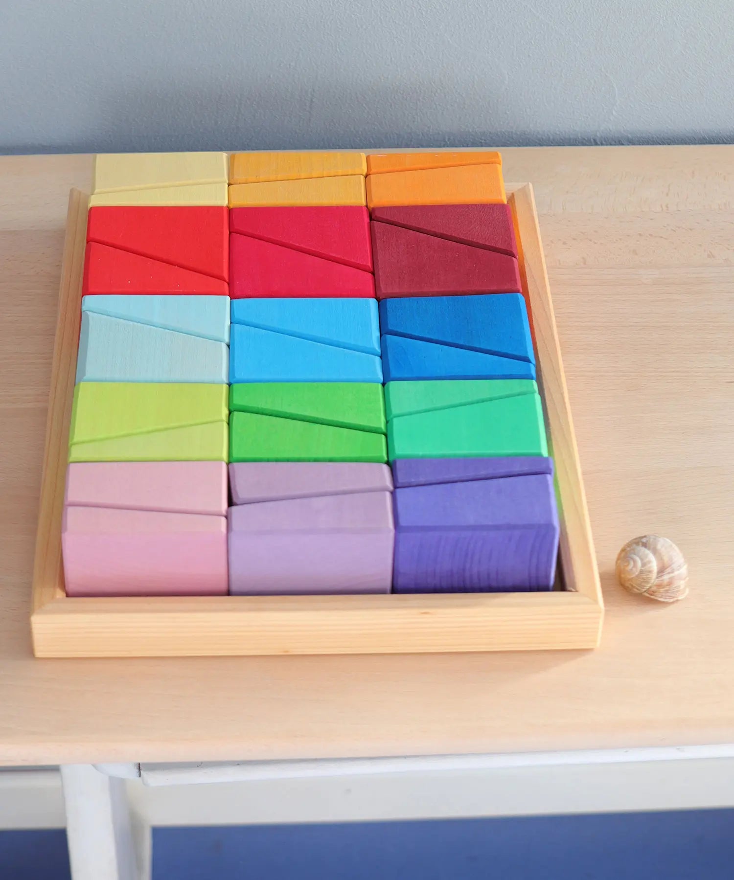 Grimm's sloping blocks building set in a wooden storage display tray placed on a wooden surface.