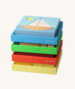 Four Grimm's building sets stacked up. The blue sailing boat design set is on the top.Four different sets each containing a set of shaped blocks that sit in a coloured wooden storage tray. These Grimm's toys are part of a wide range of wooden toys available here at Babipur. 