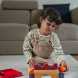 A child playing with the Grimm's red car stacking puzzle building block set. These Grimm's toys are part of a wide range of wooden toys available here at Babipur. 