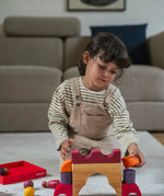A child playing with the Grimm's red car stacking puzzle building block set. These Grimm's toys are part of a wide range of wooden toys available here at Babipur. 