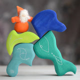 Grimm's handcrafted wooden casa aqua blocks stacked with a small dwarf doll standing on top