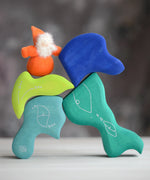 Grimm's handcrafted wooden casa aqua blocks stacked with a small dwarf doll standing on top