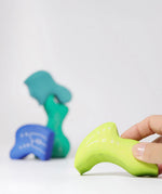 Adult holding a piece from the Grimm's casa aqua wooden toy stacking puzzle. Four piece simple wooden block puzzle toy in a mix of blue and green colours. 