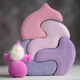 Grimm's handcrafted wooden casa coral set with a small dwarf doll standing on top. Building blocks in shades of purple