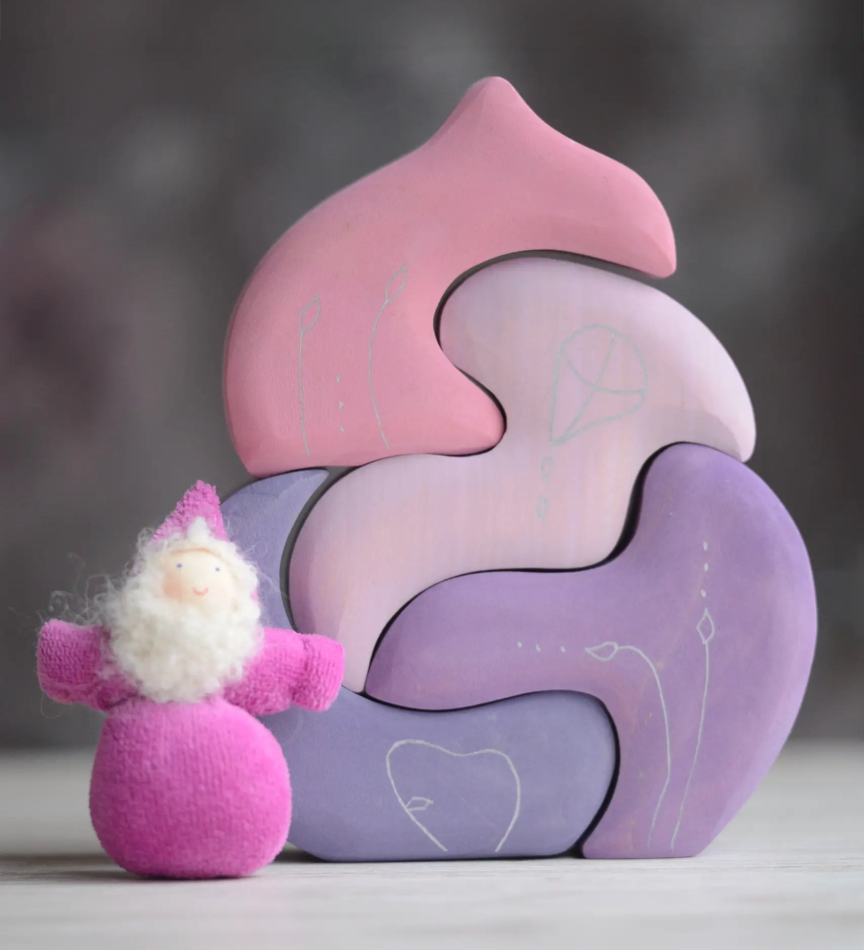 Grimm's handcrafted wooden casa coral set with a small dwarf doll standing on top. Building blocks in shades of purple