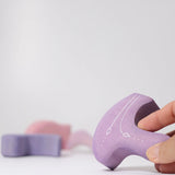 Adults holding a piece from the Grimm's casa coral wooden toy stacking puzzle. Four piece pink and lilac block puzzle. 