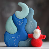 Grimm's handcrafted wooden casa luna set with a small dwarf doll standing on top. Building blocks in shades of blue