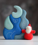Grimm's handcrafted wooden casa luna set with a small dwarf doll standing on top. Building blocks in shades of blue