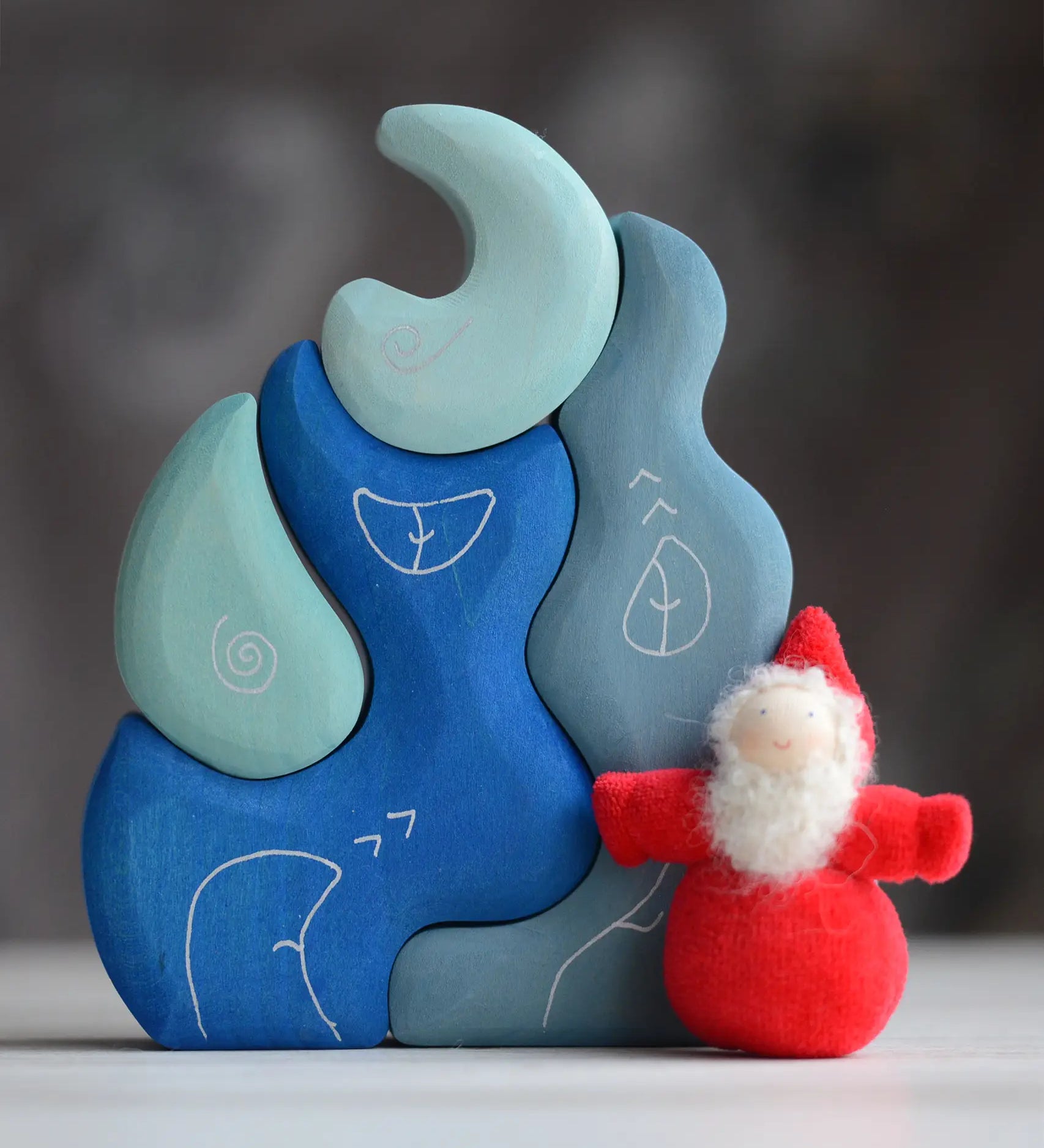 Grimm's handcrafted wooden casa luna set with a small dwarf doll standing on top. Building blocks in shades of blue