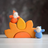 Grimm's handcrafted wooden casa sole set with small dwarf dolls standing on top. Building blocks in warm yellow and orange colours