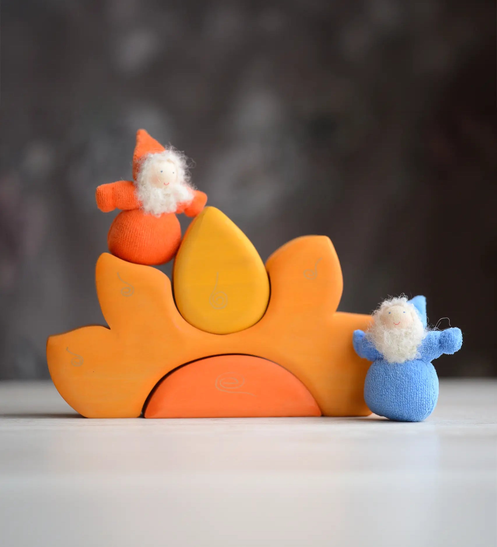 Grimm's handcrafted wooden casa sole set with small dwarf dolls standing on top. Building blocks in warm yellow and orange colours