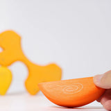 Adult's hand holding a piece of the Grimm's casa sole sun shaped wooden stacking toy. Three piece puzzle.