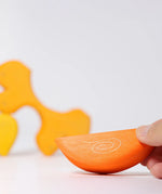 Adult's hand holding a piece of the Grimm's casa sole sun shaped wooden stacking toy. Three piece puzzle.